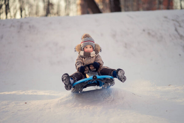 boy on the sled having fun in winter park 