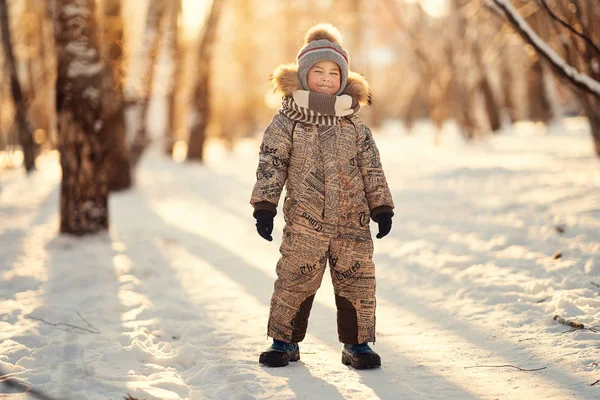 与闭着眼睛站在冬季公园的欢快的男孩的全长拍摄 — 图库照片