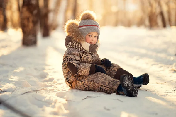 Widok Boczny Chłopiec Siedzi Śniegu Patrząc Kamery Słoneczne Zimowe Dni — Zdjęcie stockowe