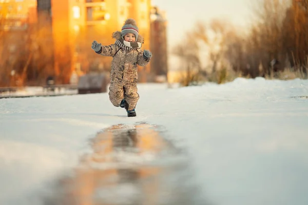 快乐男孩在冬天在街上奔跑的全长镜头 — 图库照片