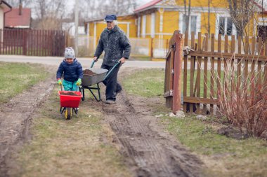 Dede ve torunu birlikte bahçe arabaları ve yere tam kullanarak yarda çalışma 