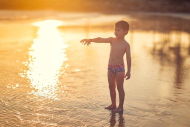 gün batımında eliyle işaret sahilde duran çocuğun tam uzunlukta atış 