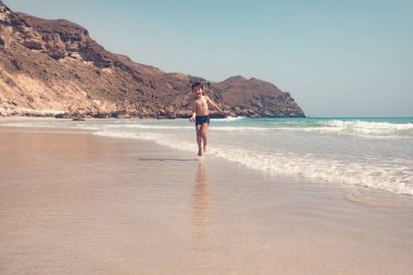 Sahilde çalıştıran ve having fun güneşli günde çocuğun tam uzunlukta 