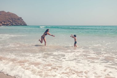  Anne ve küçük çocuk denizde oynarken birlikte eğleniyor