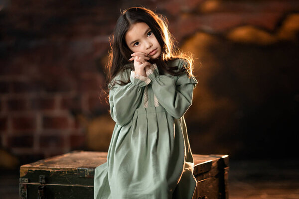 girl in green dress holding hands at the cheek and looking at the camera 