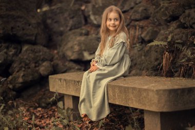 Bankta oturan ve uzağa bakan gülümseyen kız Tam Uzunlukta atış 