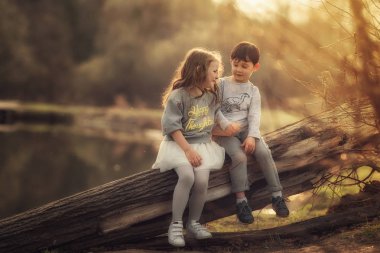 erkek ve kız kardeş bahar parkında eski günlük üzerinde oturan 