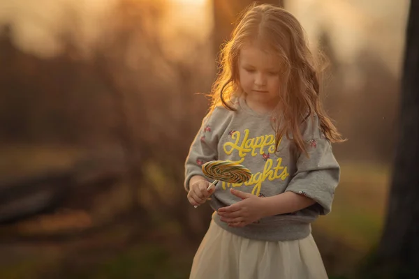 屋外で手にロリポップを見ている女の子の肖像画 — ストック写真