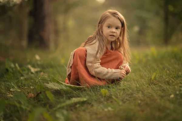 森の中の地面に座ってドレスを着てかわいい女の子 — ストック写真