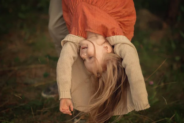 father holding his daughter upside down outdoors