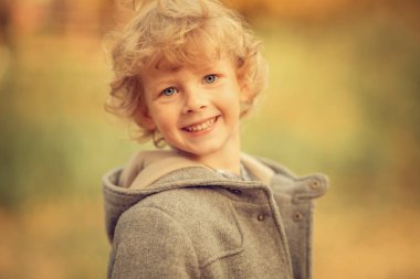 Güler yüzlü mavi gözlü çocuk gündüz vakti kameraya bakıyor. 