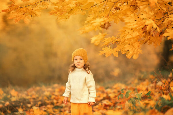 веселый ребенок в шапочке, стоящий в атомном парке и смотрящий в камеру
 