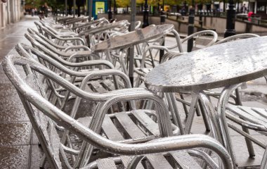Bir yağmurlu günde Paris'te bir bar teras masa ve sandalyeler ile