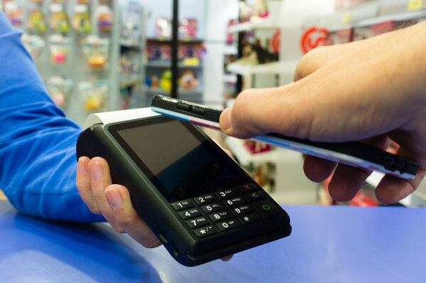 Mobile payments concept. Customer paying a merchant with mobile phone with NFC technology.
