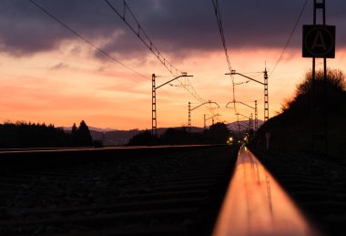 Gün batımında güzel gökyüzü tren istasyonu. Demiryolu, kırmızı bulutlar, Güneş ile renkli mavi gökyüzü, endüstriyel yatay
