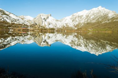 Karla kaplı tepeler bir göl içinde Barrios De Luna, Leon, İspanya, bir güzel kış akşamı yansıtılır