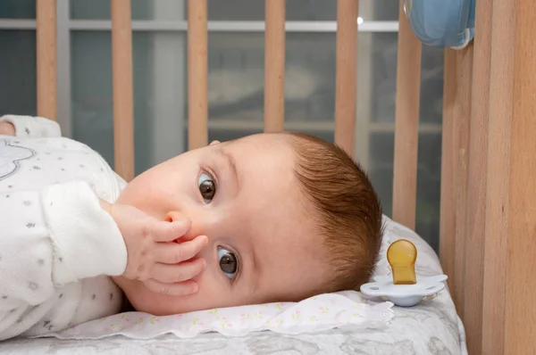küçük bebek ağzına parmak emme karyola üzerinde yatıyordu. Dikey yatay görüntü