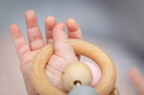 Ahşap bir oyuncakla oynamak bir bebek el kapatın. Odaklanmamış arka plan