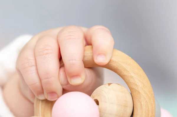Ahşap bir oyuncakla oynamak bir bebek el kapatın. Odaklanmamış arka plan