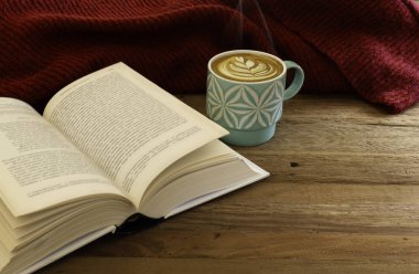 Hayat ayrıntıları, bir fincan latte ya da bir kitapla kapuçino kahve ve ahşap bir masada kırmızı süveter..