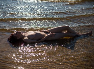 Denizde poz güzel çıplak genç kadın. Seksi çıplak redhead yaz sahilde günbatımı zevk.