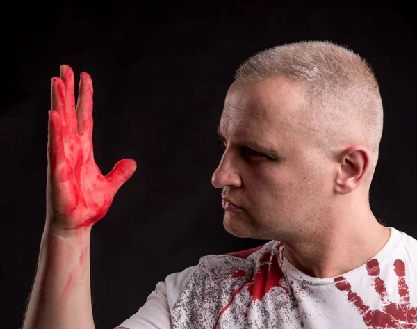 Portrait of  man with bloody hand posing on a black background