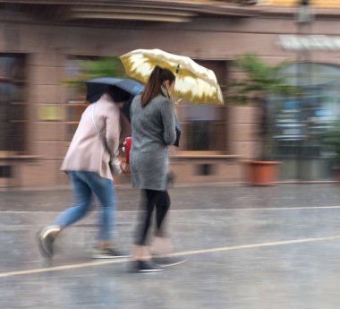 Yağmurlu gün sokakta umbrellawalking insanlarla. Kasıtlı hareket bulanıklığı