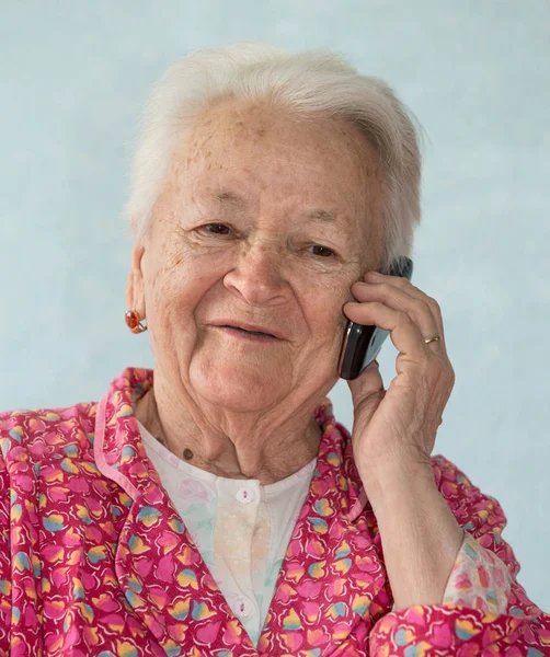 在家里用手机说话的老微笑的女人 — 图库照片