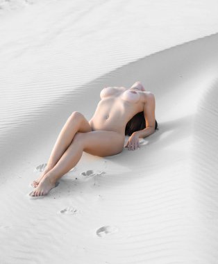 Kumlu bir plaj üzerinde poz çıplak kadın. Seksi kadının sıcak yaz günü açık havada