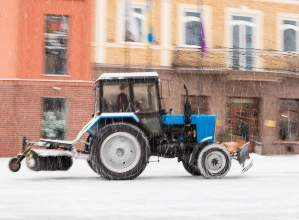 Snow removal machine cleaning the street from snow. Snowplow truck removing snow on the street after blizzard. Intentional motion blur