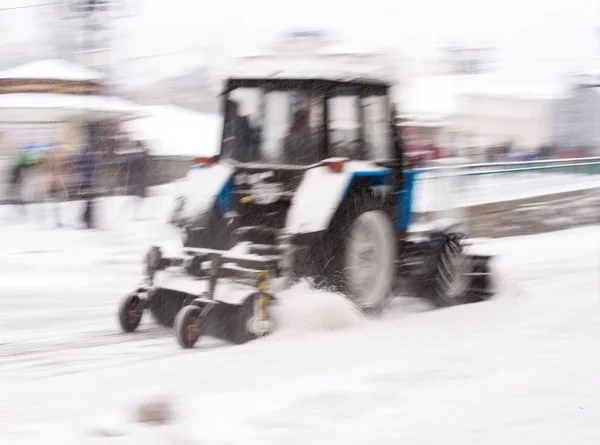 Snow removal machine cleaning the street from snow. Snowplow truck removing snow on the street after blizzard. Intentional motion blur