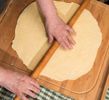 Fırını dükkanında klasik kruvasan üreten. Kadın hamur içine daha fazla pişirme için rulo haddeleme