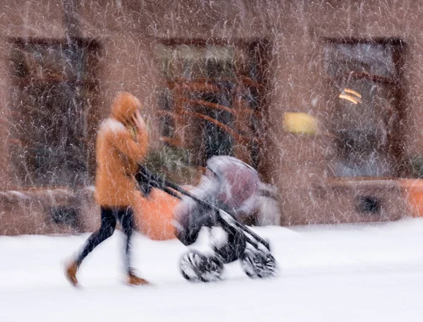 父は雪の降る冬の日にベビーカーで子供と歩きます 意図的なモーションブラー イメージ — ストック写真