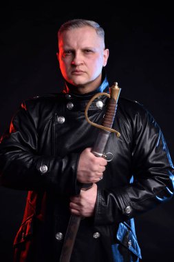 Kılıç tutan bir siyah arka plan üzerine siyah ceketli yakışıklı adam