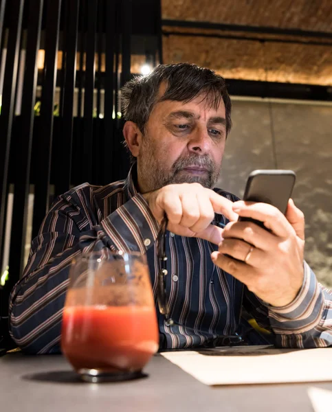 在咖啡馆里 穿着便装的老人用手机 — 图库照片