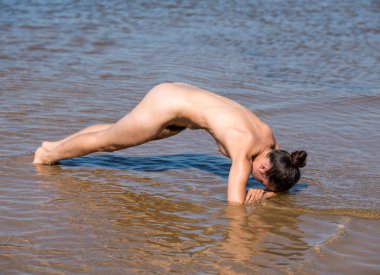 Denizde poz veren güzel çıplak genç bir kadın.
