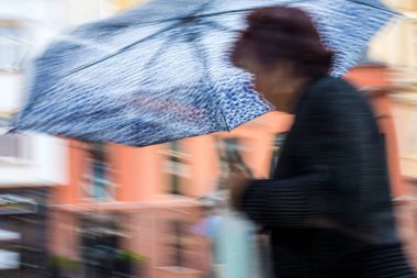 Yağmurlu günde sokakta şemsiyeli insanlar yürüyor