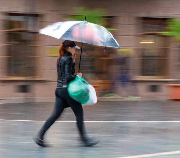 Menschen mit Regenschirm laufen an einem regnerischen Tag die Straße entlang — Stockfoto
