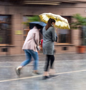 Yağmurlu günde sokakta şemsiyeli insanlar yürüyor