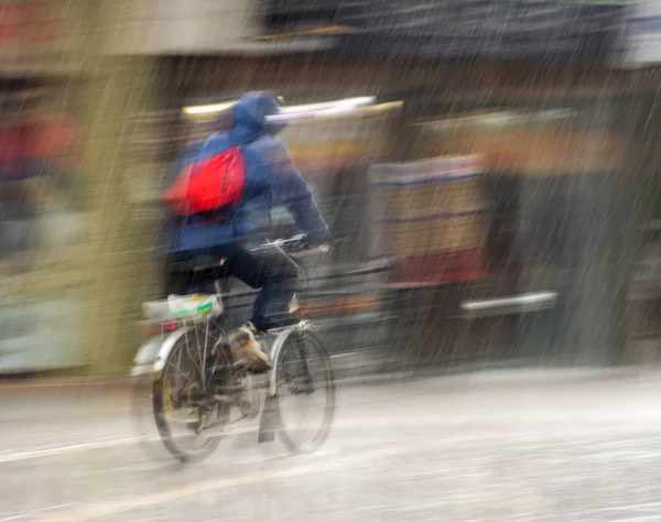 Ciclista en la carretera de la ciudad en movimiento borrosa en días lluviosos. Intenti —  Fotos de Stock