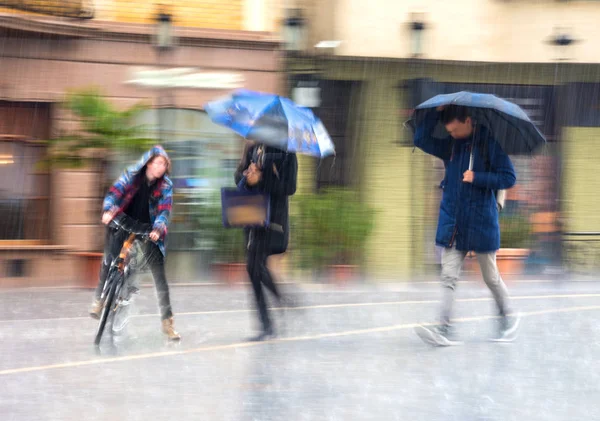 Люди с зонтиком идут по улице в дождливый день — стоковое фото