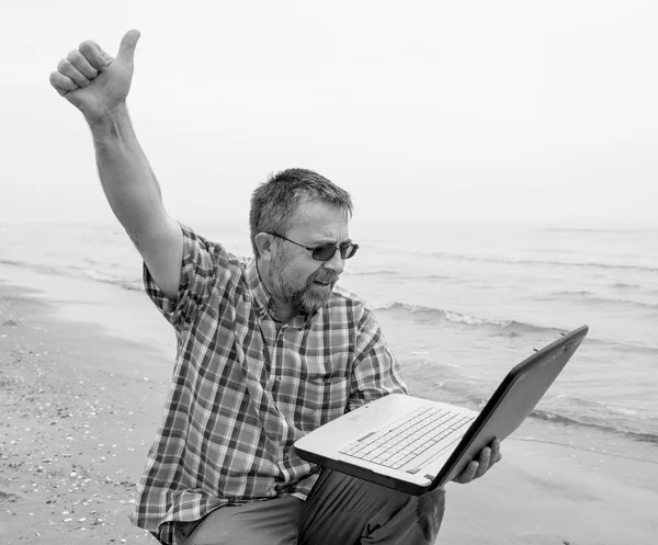 Man sitter med laptop på stranden — Stockfoto