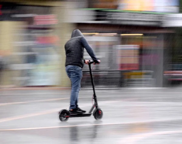 Uomo a cavallo su scooter in caso di pioggia — Foto Stock