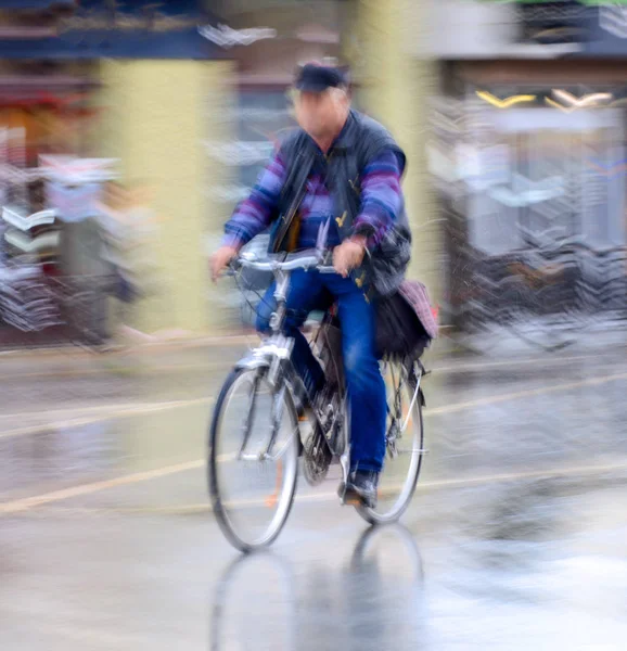 Cyclist on the city roadway in motion blur in rainy day — Stock Photo, Image