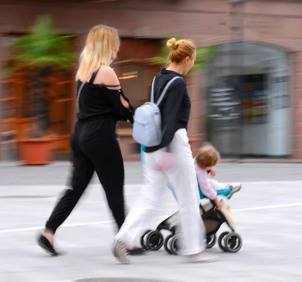 Jovem mãe com criança pequena no carrinho andando pelos s — Fotografia de Stock