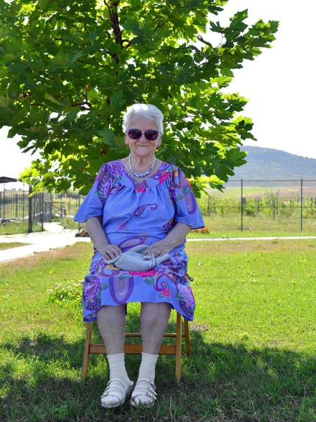 Sungalsses yaşlı gülümseyen kadın bir sandalyede oturan — Stok fotoğraf