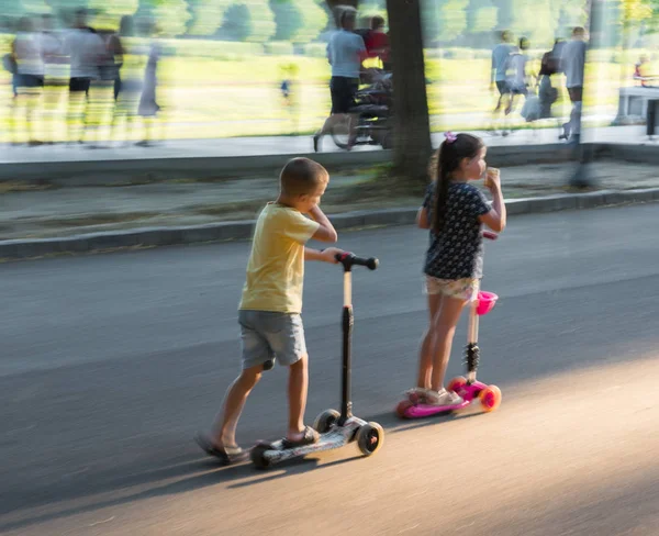 Bambini che cavalcano scooter all'aperto. Street sfondo urbano — Foto Stock