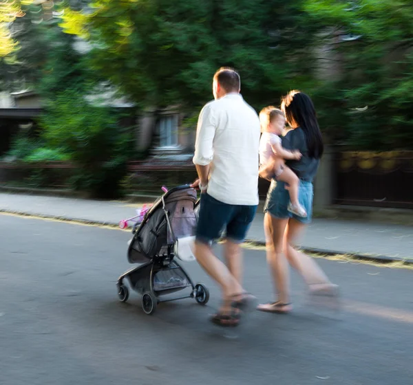 Famille avec petit enfant dans la poussette marchant dans la rue — Photo