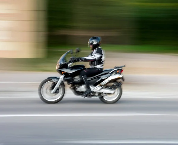 Motorcyclist in motion riding down the street . Intentional moti — Stock Photo, Image
