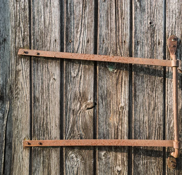 Dikey plakalı ahşap kapı ve paslı demir kapı menteşesi — Stok fotoğraf